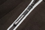 Close-up of a black fabric with a white zipper, featuring a black pull embossed with the Maserati logo.