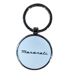 A chrome metal keyring with a polished white resin coating, featuring the Maserati logo lasered on it. The keychain is circular with a visible branding on both sides.